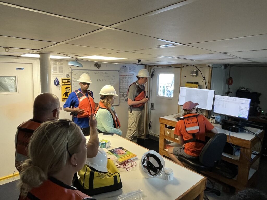 JHS educators and SkIO scientists watch as graduate student Patrick Duffy monitors a computer screen displaying images of passing plankton.