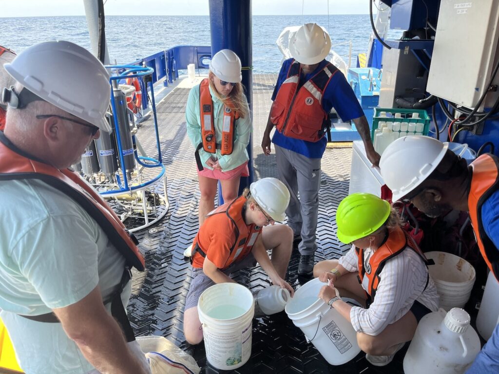 JHS educators and SkIO scientists watch as graduate students Patrick Duffy (left) and Grace Mann (right) transport water rich with plankton