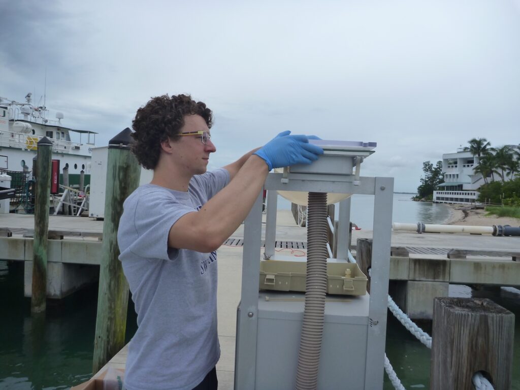 Sheridan (in 2018) loading a filter into a high-volume aerosol sampler on the Rosenstiel School of Marine, Atmospheric, and Earth Science’s dock.