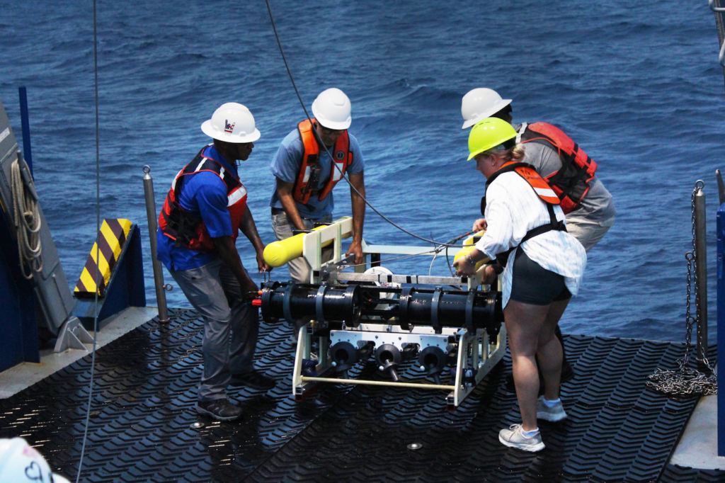 Principal Muhammad (left) helps SkIO scientists hoist the image capturing device into the water. 