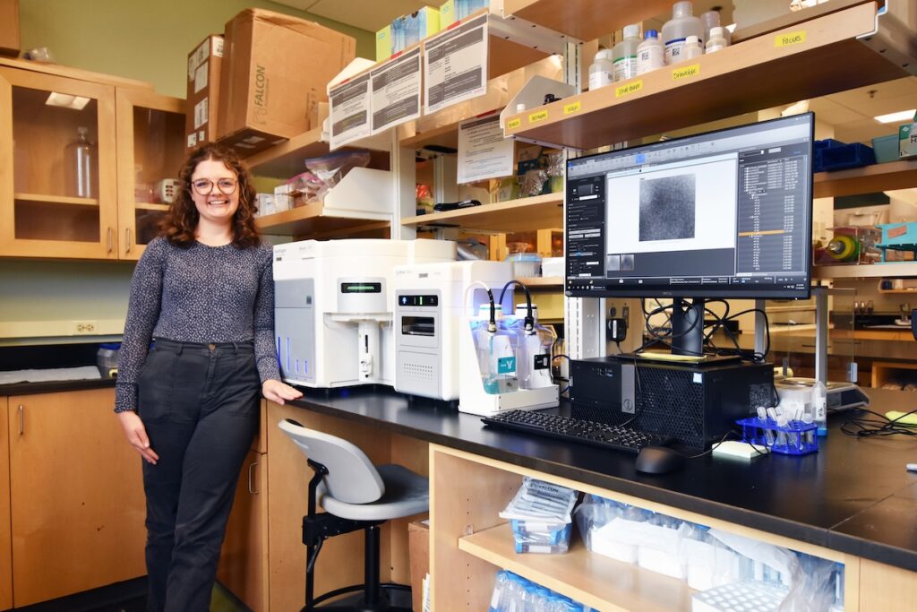 Claire Zwiers Cook, a doctoral student in Natalie Cohen’s lab, stands next to the new Attune CytPix Flow Cytometer. 