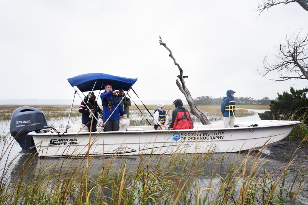 Clark Alexander, director of SkIO, speaks to Semester at Skidaway students about the geological development of Wassaw while on a field trip to the uninhabited island. He's standing in a boat on the shore of the island. 