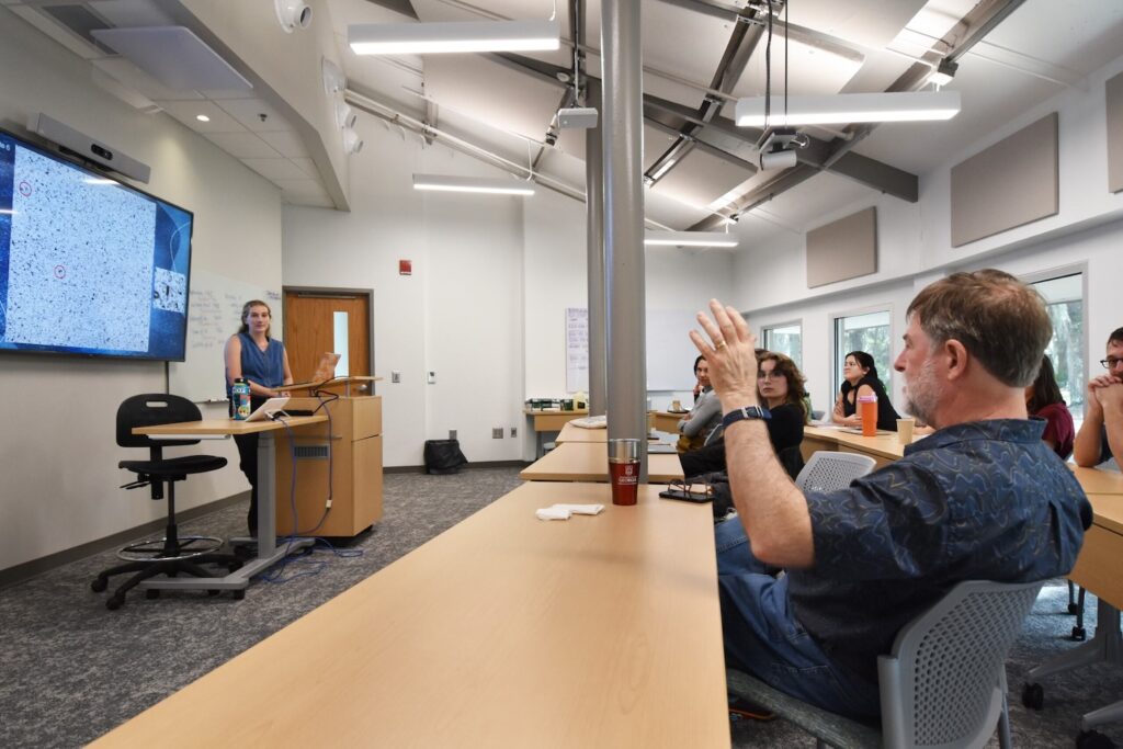 Clark Alexander, director of SkIO, raises his hand to ask Brigitte Lueder a question during her final research presentation.